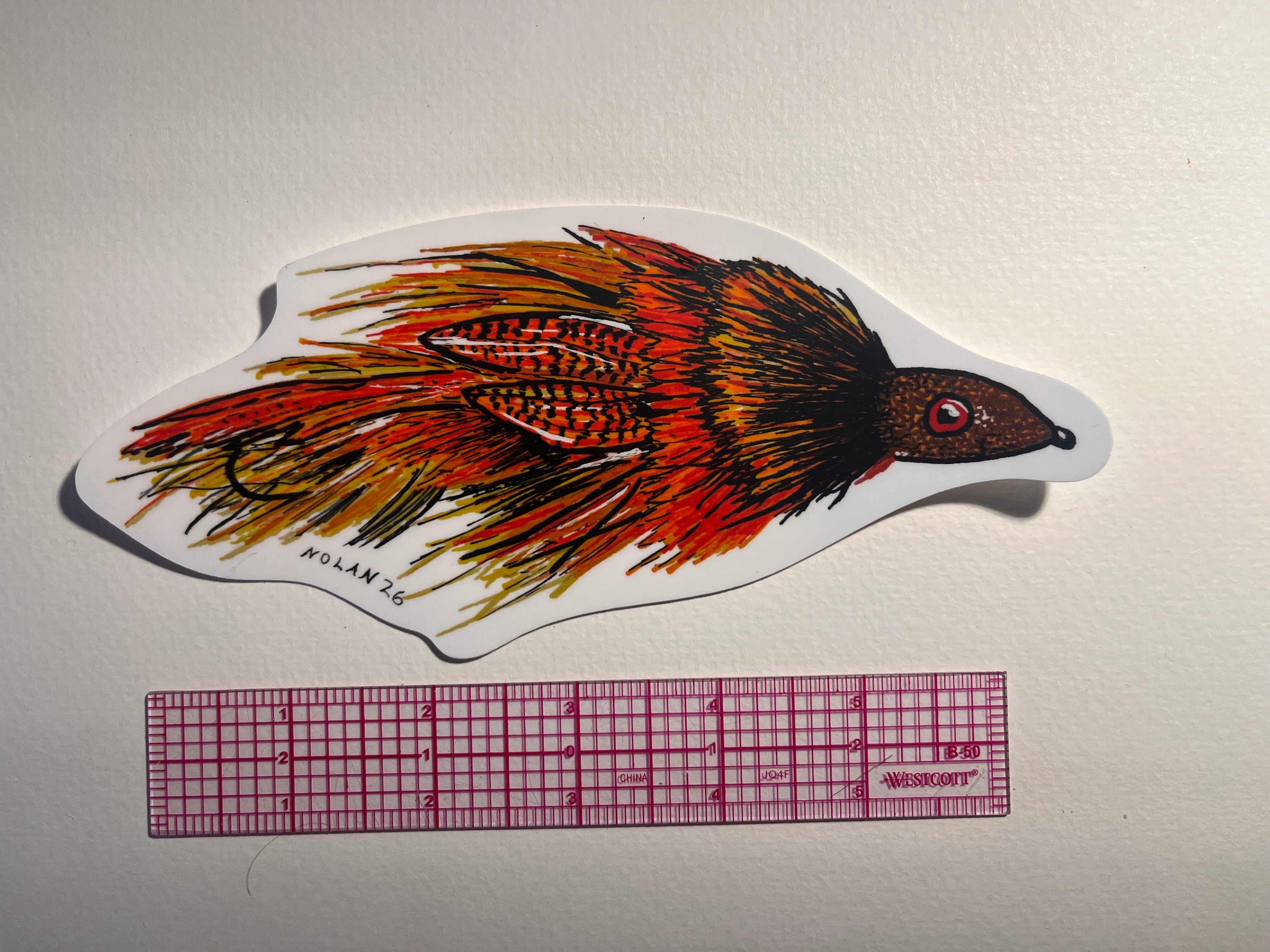 Fly Fishing Streamer with a ruler for scale on a white background